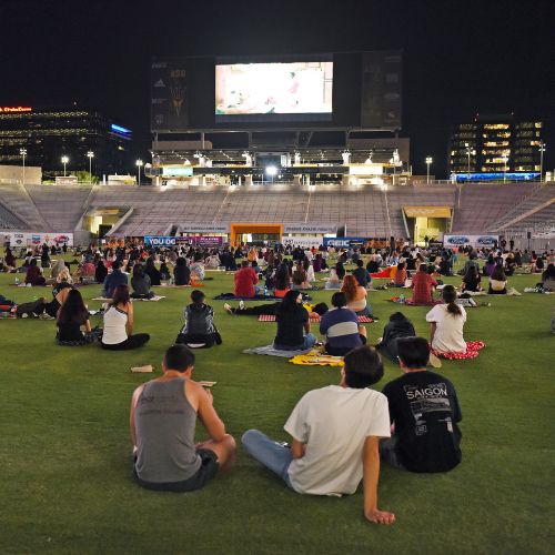 Students sit on the grass for Movies on the Field