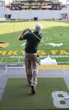 Golfer swinging a golf club on to the football field