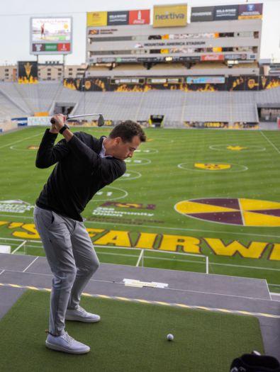 Solo golfer hitting golf balls onto the painted field at Mountain America Stadium, Home of the ASU Sun Devils