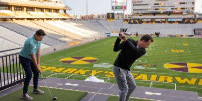 Golfers hitting golf balls onto a painted football field at Mountain America Stadium, Home of the ASU Sun Devils