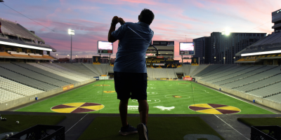 Man in final golf pose with purple and pink Tempe skies